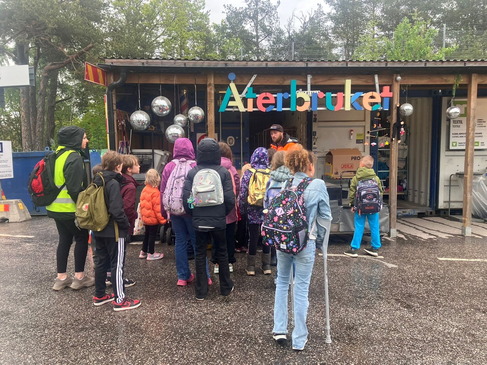 Elever med ryggsäckar samlade utanför Återbruket under ett studiebesök.