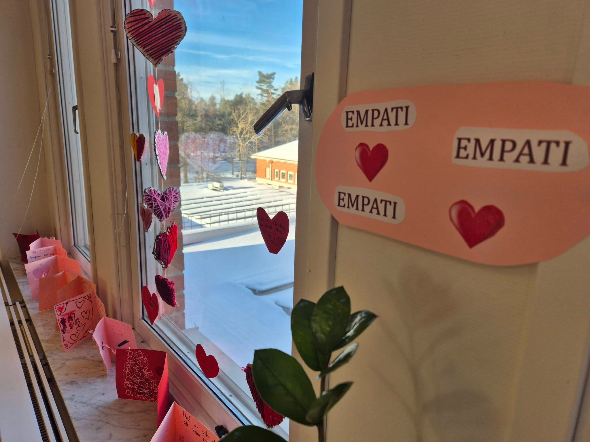 Skylten med ordet EMPATI tillsammans med röda pappershjärtan hänger i ett fönster på skolan.