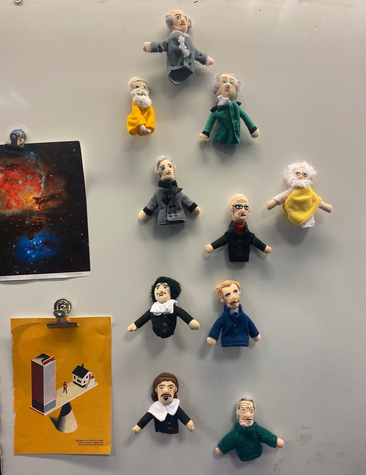 Tio fingerdockor av kända filosofer hänger på en magnetisk vägg i klassrummet.