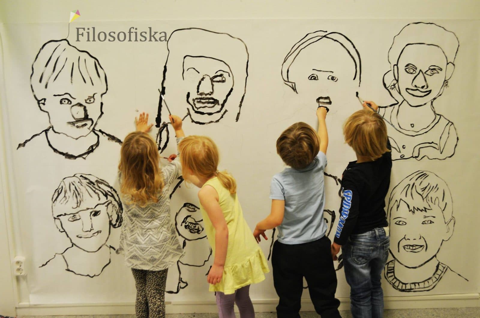 Förskolebarn i Enskededalen tittar på en vägg full av gemensamt tecknade porträtt.