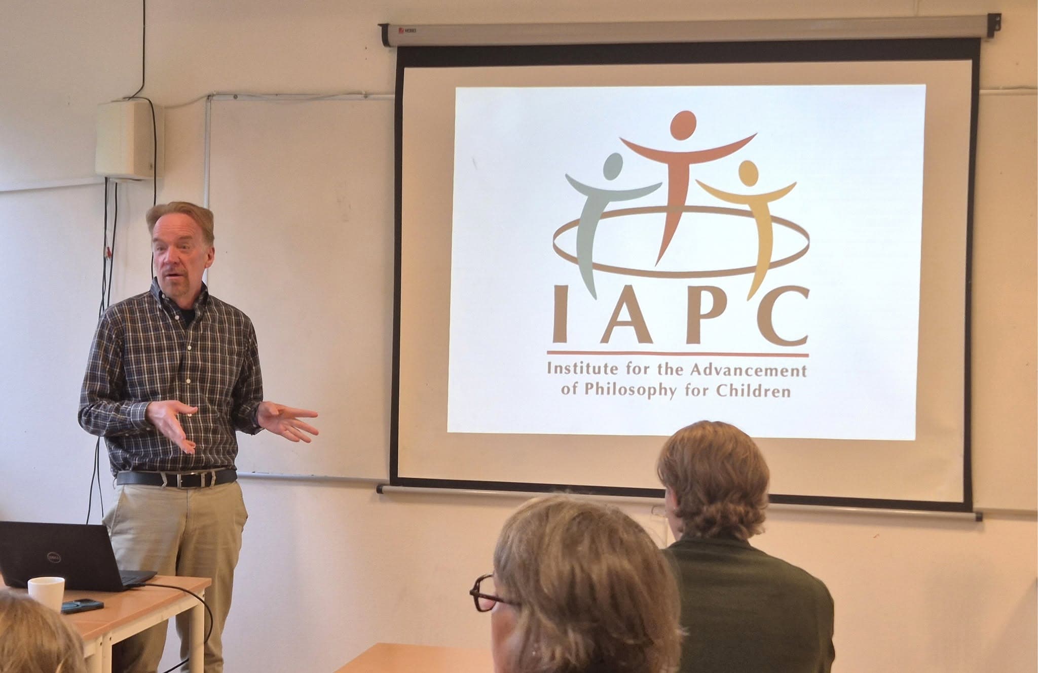 Professor Maughn Gregory föreläser för personalen framför en bild med IAPC:s logotyp.