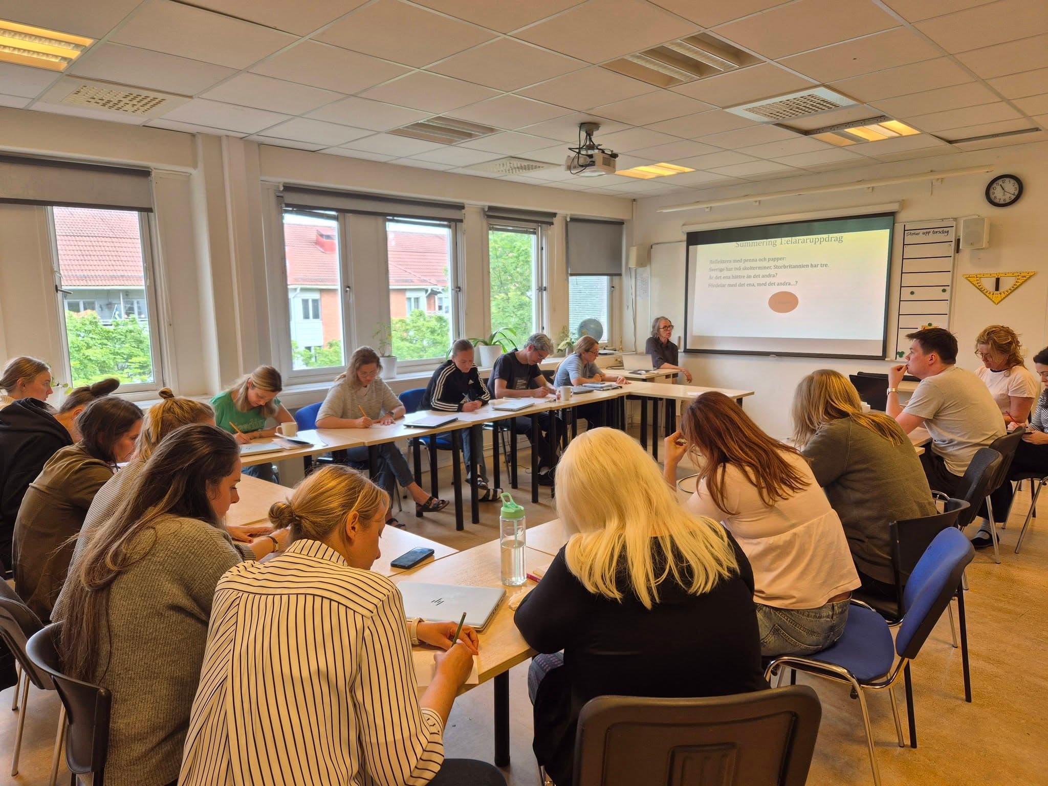 Personalen sitter samlad kring bord med anteckningsblock under en fortbildningsdag.