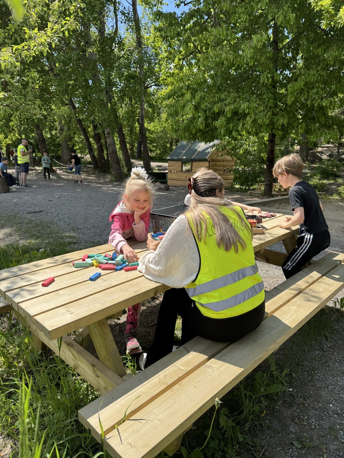 Elever i varselvästar tar en paus vid ett picknickbord under en utflykt.